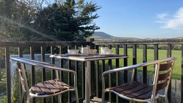 Ein Tisch mit Stühlen und Blick auf ein grünes Feld und einen Berg.