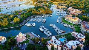 A marina with numerous boats docked, surrounded by residential buildings and lush greenery. - Hilton Head Luxury Condo! Coligny, Dining, Family, Golf - Sleeps 10 
 STR#045066 (Hilton Head Island)