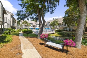 Stroll along the serene pathway to a peaceful seating area surrounded by mature trees and hotel views.