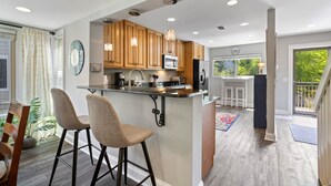 A modern kitchen with wooden cabinets, a central island with bar stools, and pendant lighting. - Hilton Head Luxury Condo! Coligny, Dining, Family, Golf - Sleeps 10 
 STR#045066 (Hilton Head Island)