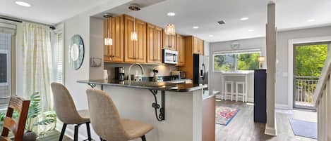 Una cocina moderna con armarios de madera, una isla central con taburetes y luminarias colgantes.