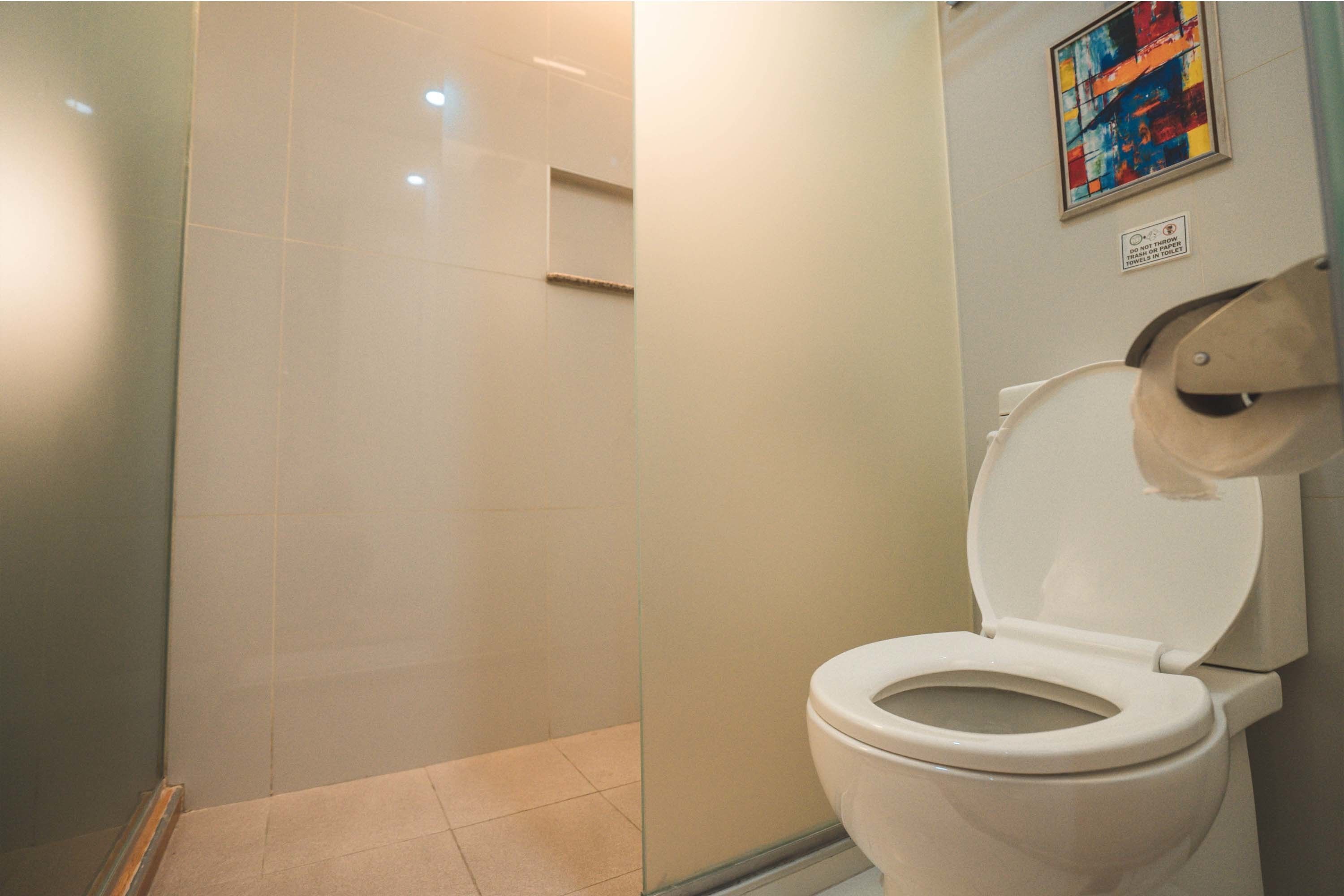 Een badkamer met een toilet, een douche en een betegelde vloer.