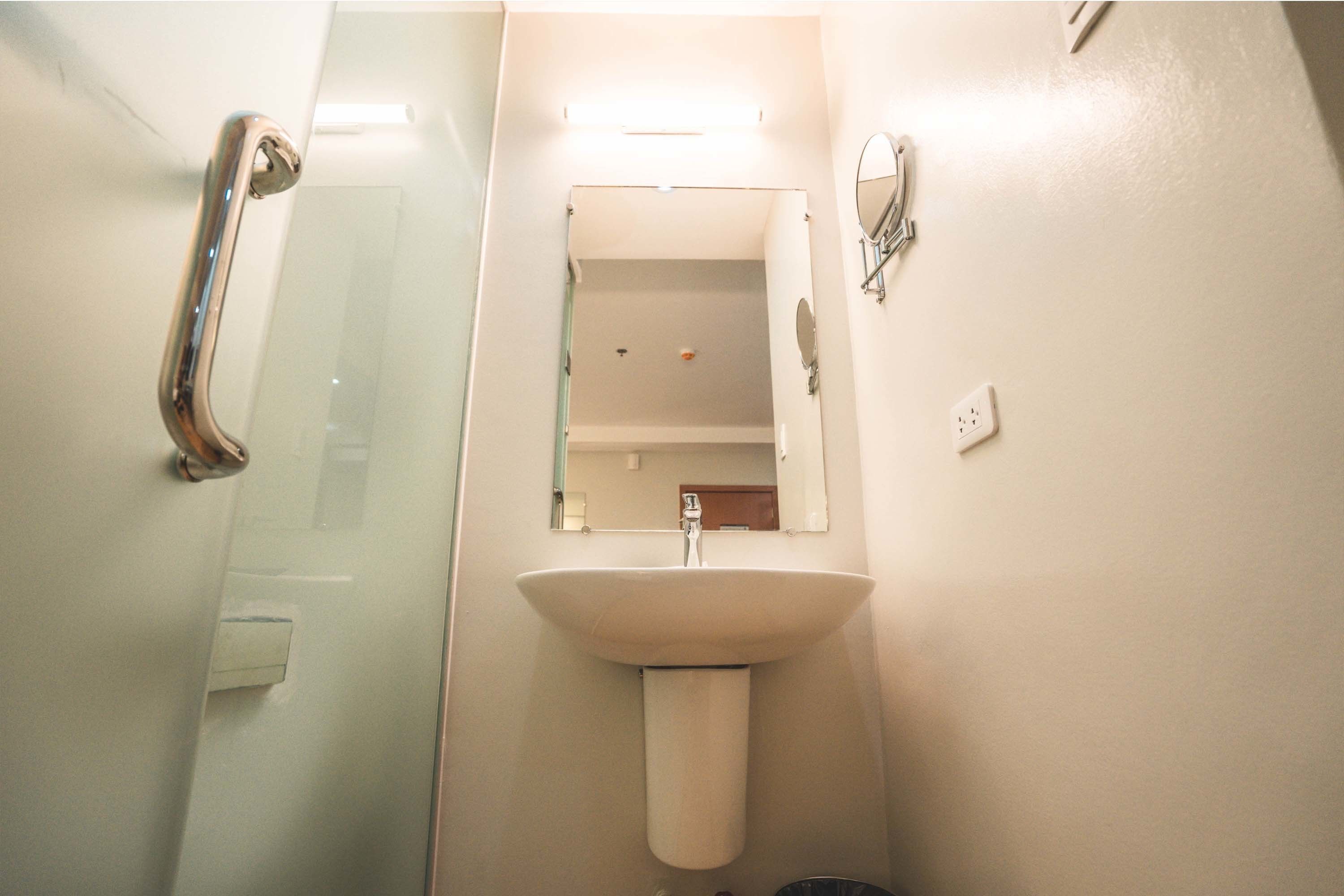 Un baño con lavabo blanco, espejo y cabina de ducha de vidrio.