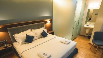 A hotel room with a bed, bedside tables, a chair, a bathroom with a sink, and a mirror.