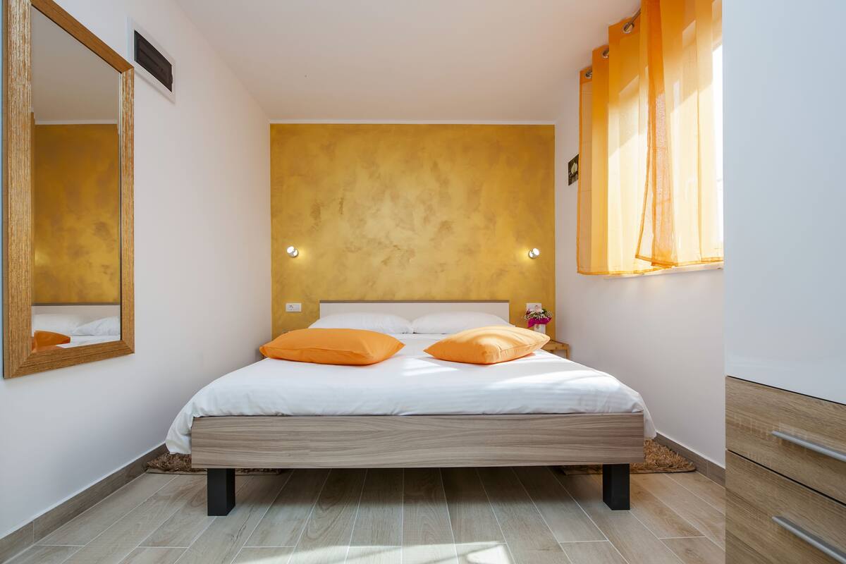 Um quarto com uma cama, um espelho e uma janela com cortinas.