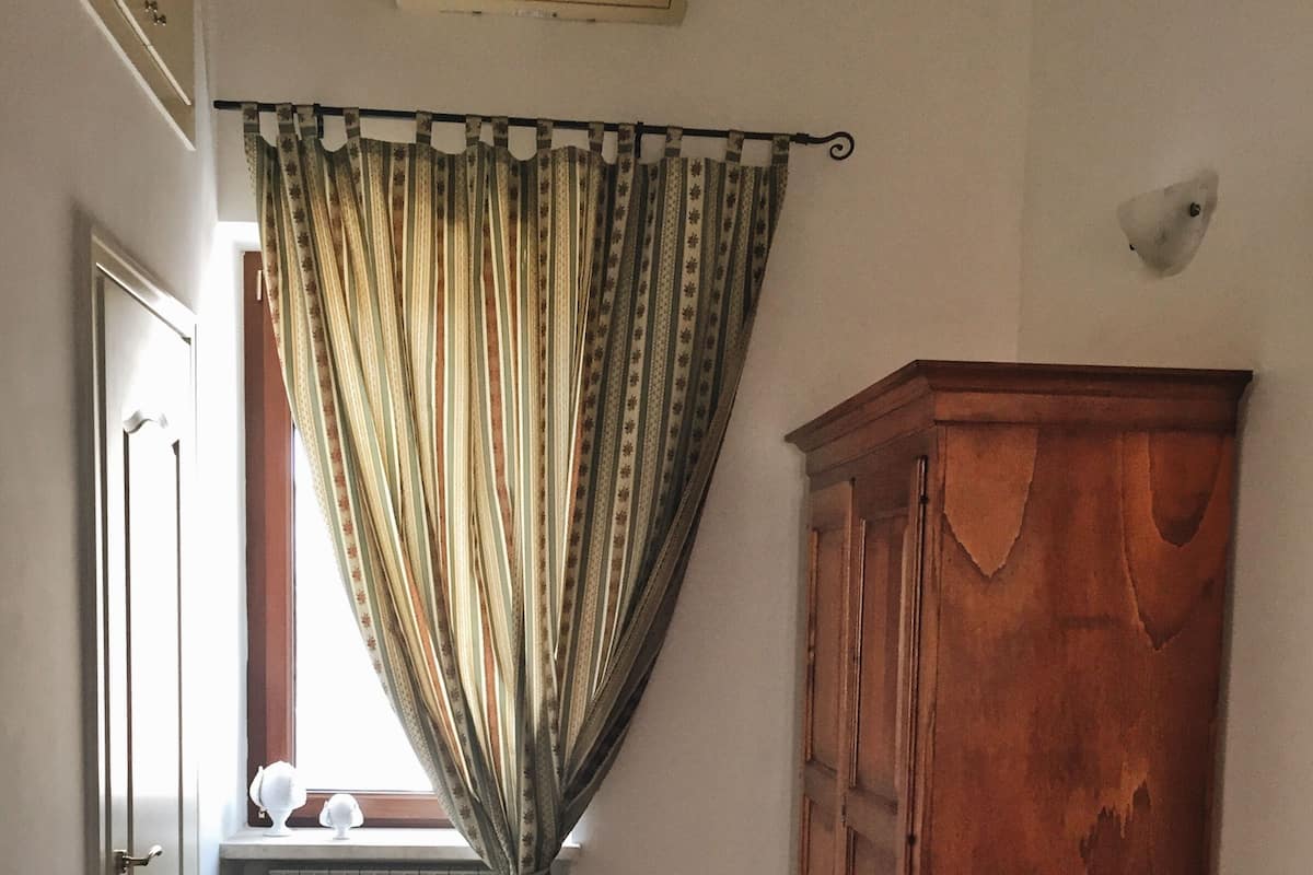 A room with a radiator, a wooden cabinet, and a window with curtains.