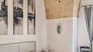 Un dormitorio con una cama, una mesita de noche, una silla y tres cuadros en la pared.