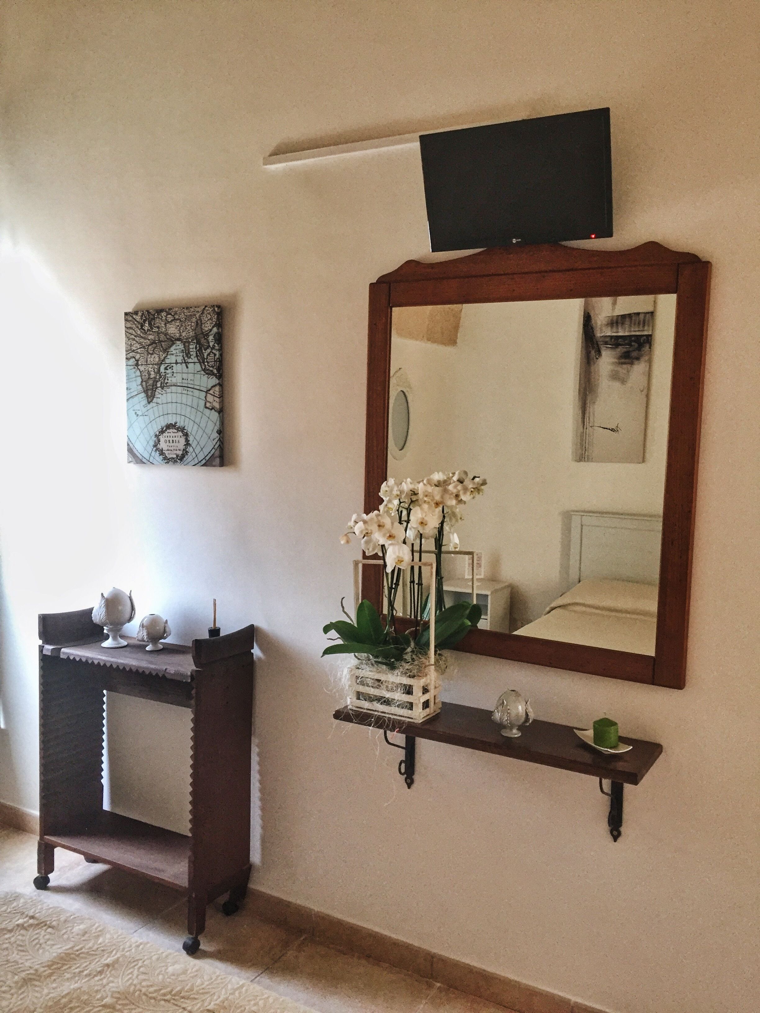 A room with a wooden console table, a mirror, and a globe artwork on the wall.