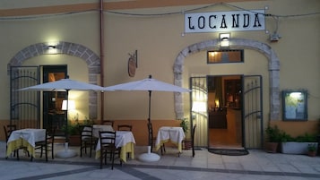 Zona de estar al aire libre con mesas y sombrillas en Locanda.