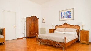 Un dormitorio con una cama de madera, un armario, un radiador y un cuadro en la pared.