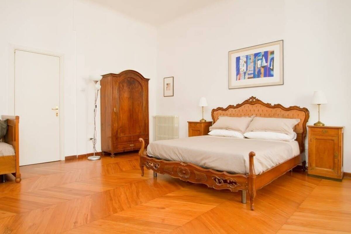 Un dormitorio con una cama de madera, un armario, un radiador y un cuadro en la pared.