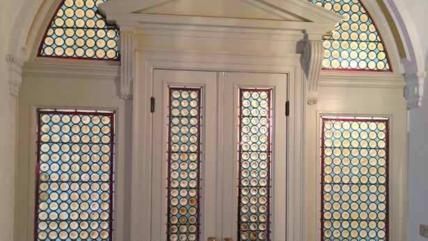 Puerta blanca con un panel de vidrio decorativo y una ventana arqueada a juego arriba.