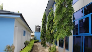A modern building with blue and white exterior walls, a narrow pathway, and green plants. - Blue Hill Hotel (Bamahu)