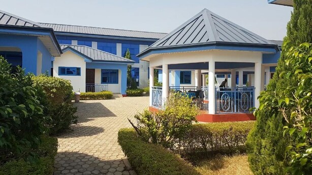 A building with a covered outdoor area, paved pathways, and neatly trimmed bushes. - Blue Hill Hotel (Bamahu)