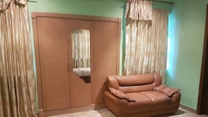 A room with a brown sofa, a wardrobe, and curtains. - Blue Hill Hotel (Bamahu)