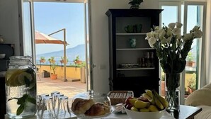 A dining area with a table set for two, a vase of white flowers, and a view of the outdoors. - Vesuvio View (Vico Equense)