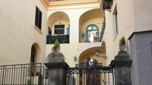 A courtyard with a gated entrance, stone pillars, and a staircase leading to an upper level. - Vesuvio View (Vico Equense)
