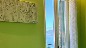 A room with a green wall, a door leading to a balcony, and a piece of abstract art. - Vesuvio View (Vico Equense)