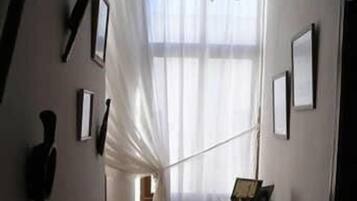 A narrow hallway with a staircase leading to a room with a large window and a table.
