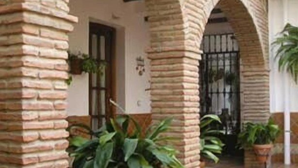 Un patio con arcos de ladrillo, plantas en macetas y suelo de baldosas.