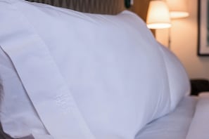 Un cuscino bianco con un logo su un letto d'hotel.