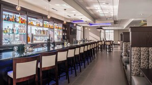A bar area with a long counter, multiple stools, and a seating area with patterned cushions.