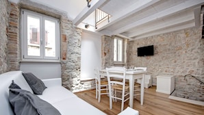 Una habitación acogedora con un sofá blanco, una mesa de comedor con sillas y una pared de piedra.