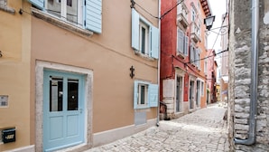 Una calle empedrada con edificios de fachadas en tonos pastel y persianas tradicionales.