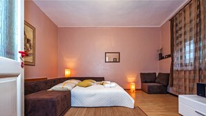 Un dormitorio con cama, sofá, televisión y una mesita.