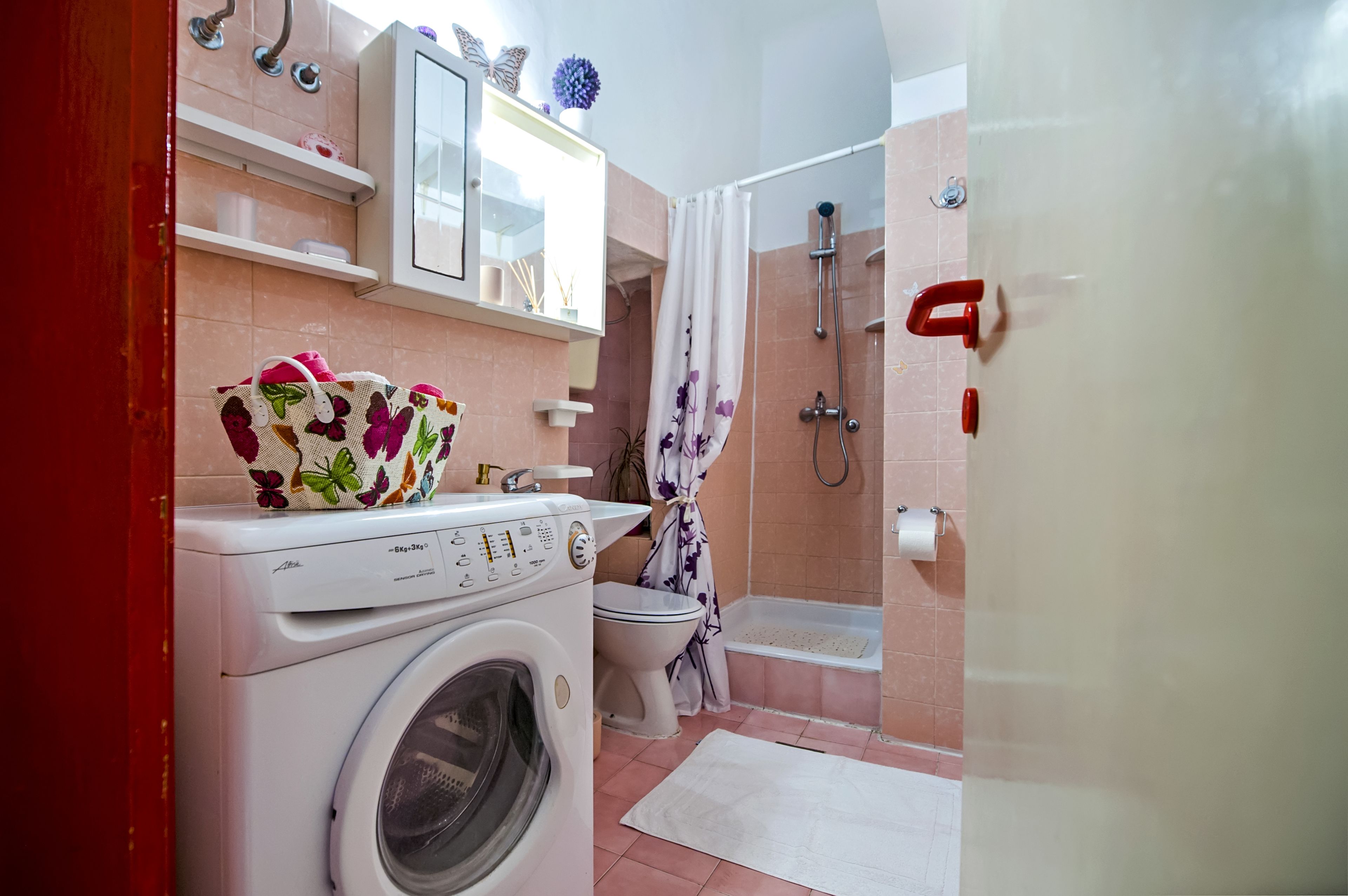 Ein kleines Badezimmer mit Waschmaschine, Toilette und Duschbereich.