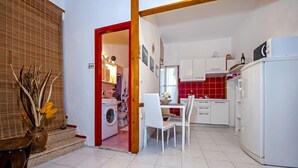 Cocina compacta con lavadora, comedor con mesa y sillas, y refrigerador.