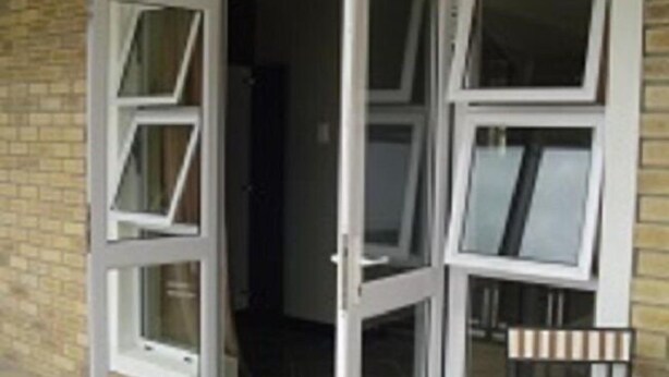 A doorway with multiple windows, a brick wall, and a metal gate. - Mount Lodge Humewood (Gqeberha (Port Elizabeth))