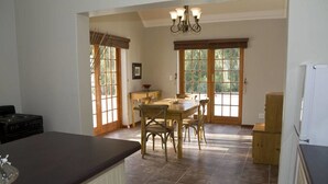 A spacious kitchen with a dining area, large windows, and a chandelier. - Lady Grey Walk Cottage (McGregor)