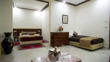 Une chambre à coucher avec un lit, une commode, un vase de fleurs et une bouteille de champagne posée sur une table.