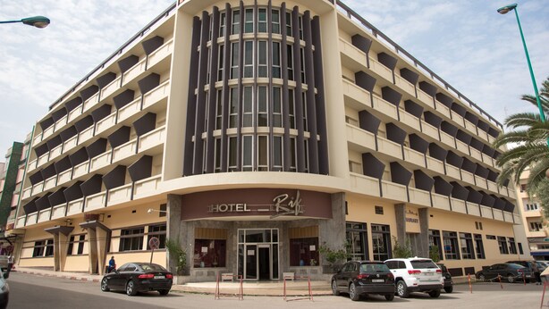 A multi-story hotel with a curved facade, multiple balconies, and a prominent entrance.