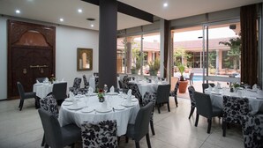 Un comedor con mesas redondas, sillas y una puerta grande de madera.