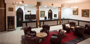 A lobby with leather chairs, a reception desk, and a chandelier.