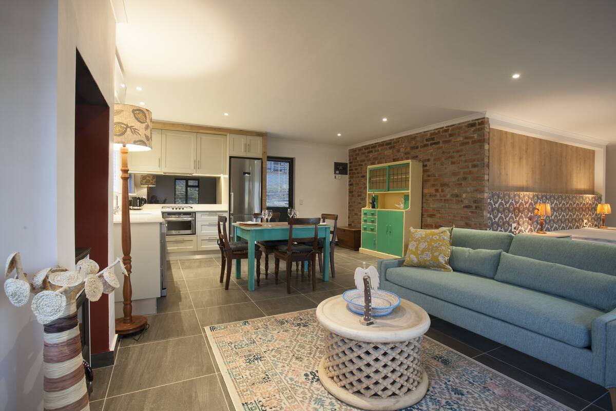 A modern living room with a sofa, a coffee table, and a dining area with a table and chairs.