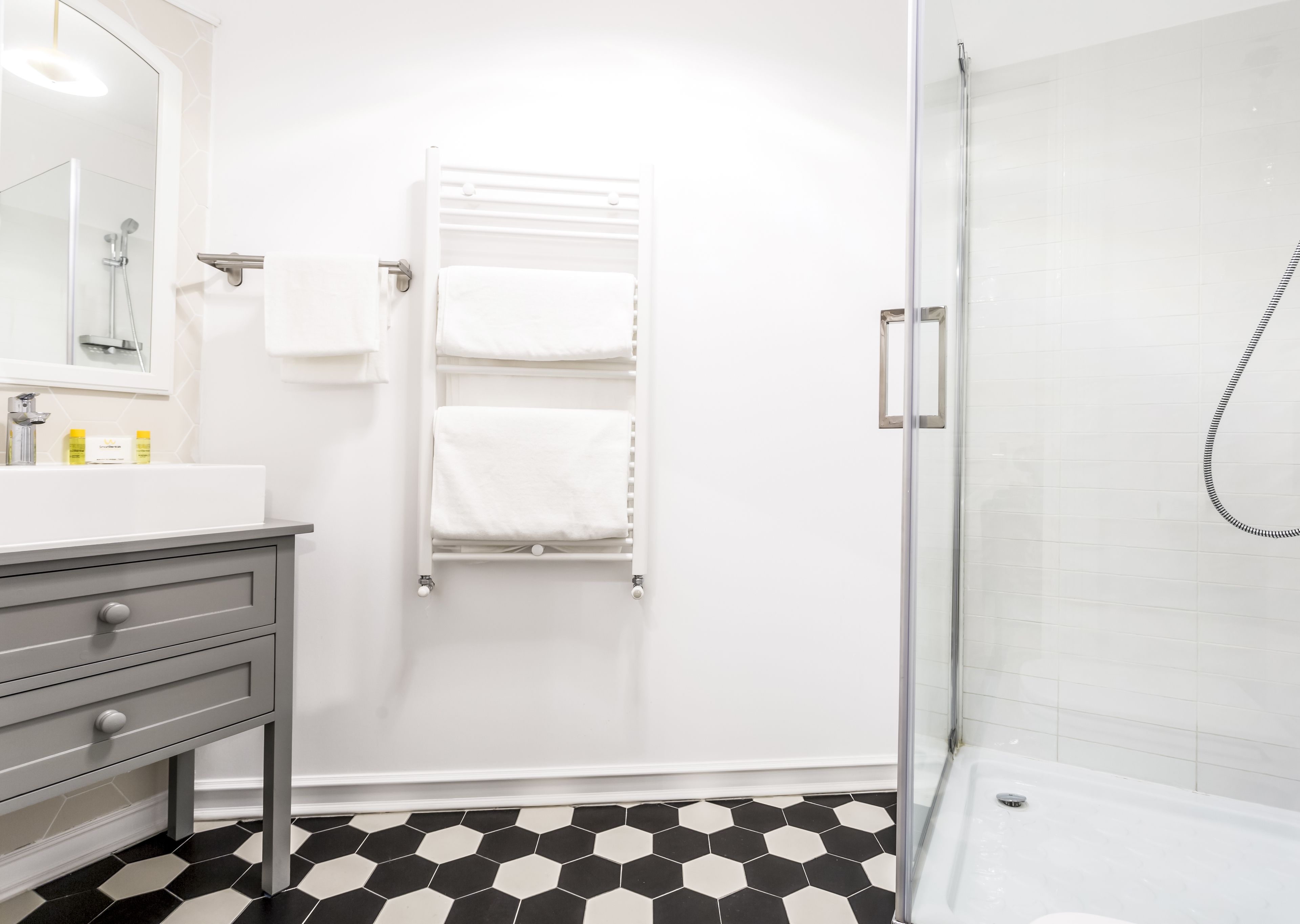 A modern bathroom with a glass shower enclosure, a white sink with a mirror, and a tiled floor.