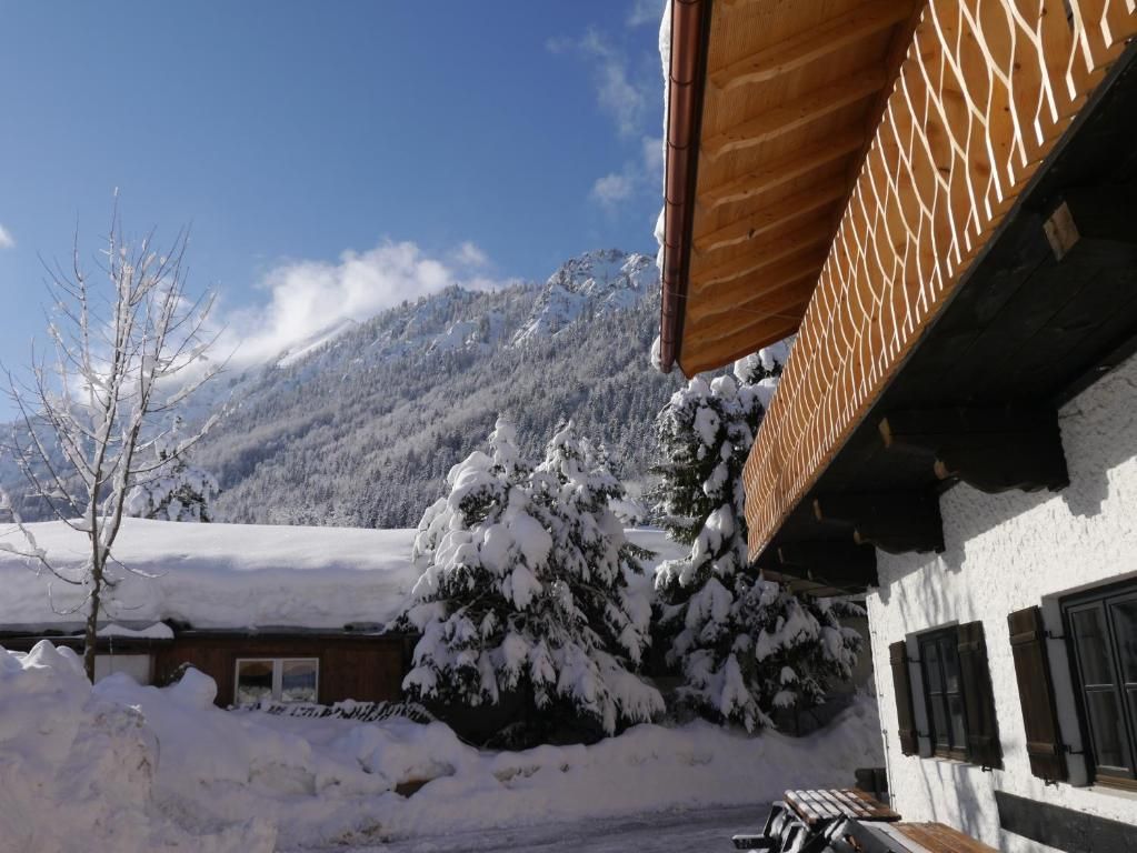 Eine verschneite Berglandschaft mit einem Gebäude, das ein schräges Holzdach und eine weiße Fassade hat.