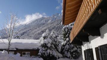 Eine verschneite Berglandschaft mit einem Gebäude, das ein schräges Holzdach und eine weiße Fassade hat.