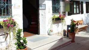 Un bâtiment à la façade blanche, doté d’un balcon en bois et agrémenté de plantes en pot.