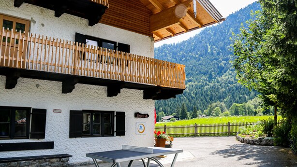 Un bâtiment doté d’un balcon en bois, d’une table et offrant une vue sur la montagne.
