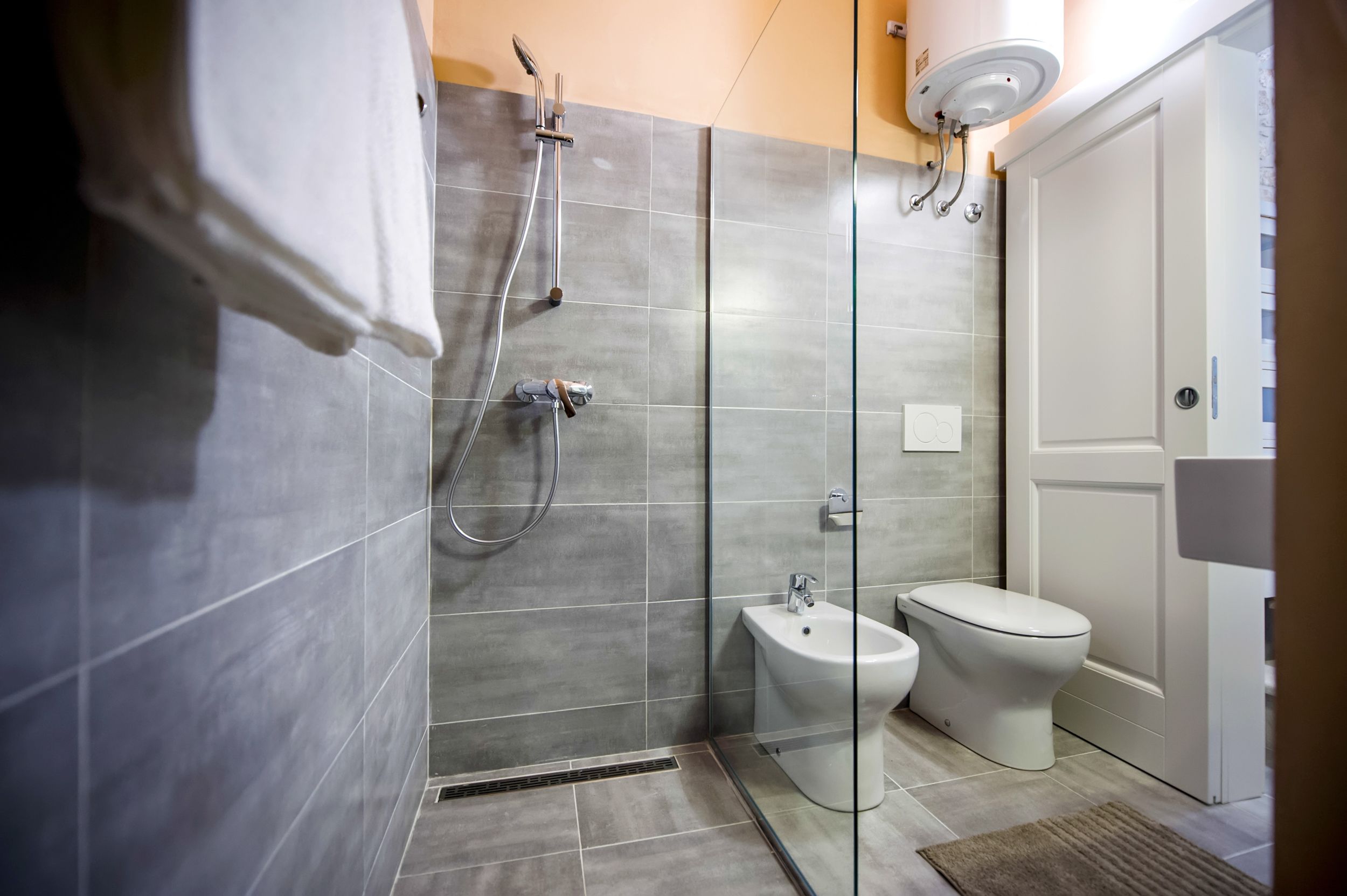 Een moderne badkamer met een douchecabine van glas, een bidet en een toilet.