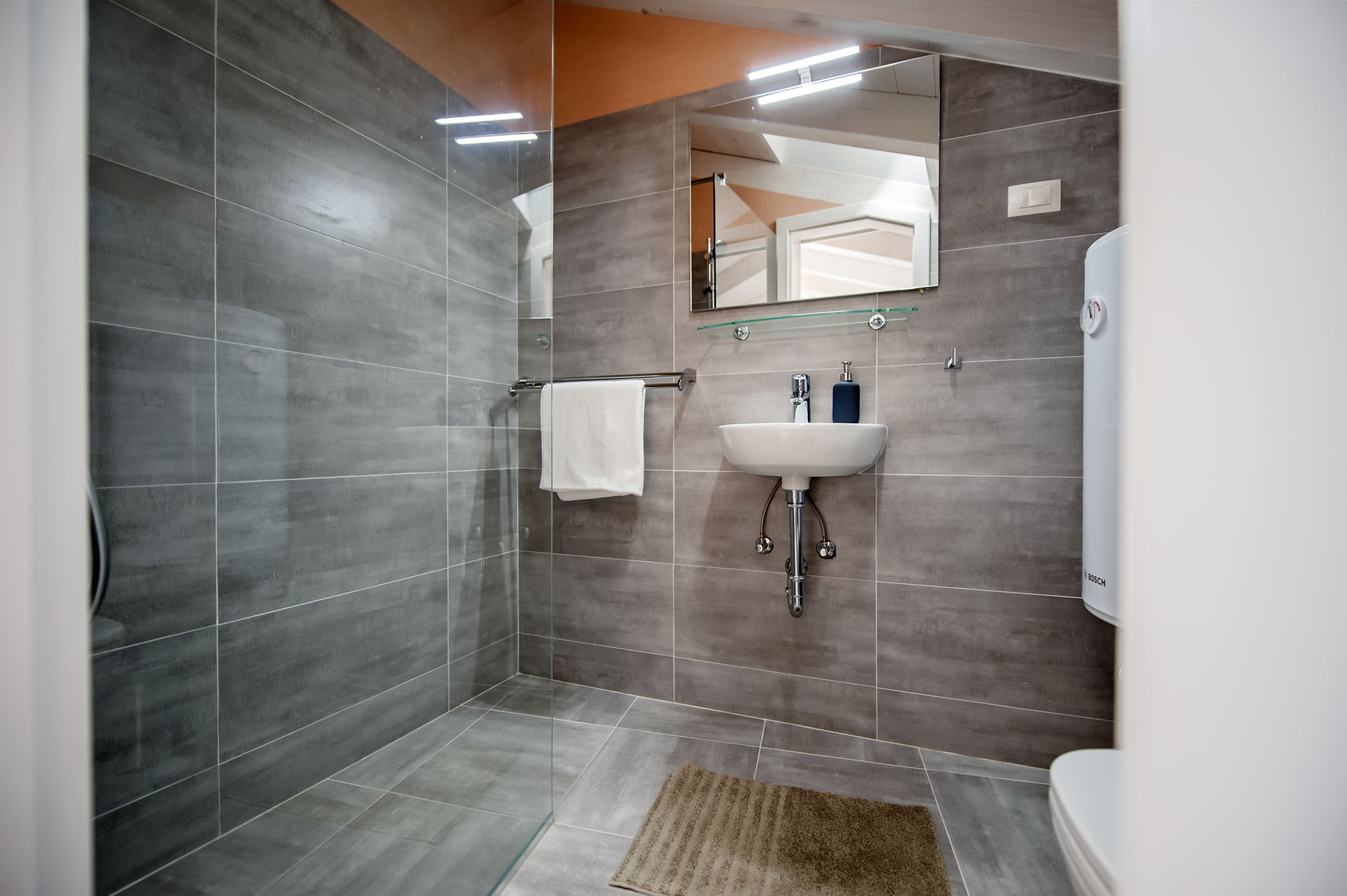 Une salle de bain moderne avec une douche à parois de verre, un lavabo blanc et des toilettes de la marque Bosch.