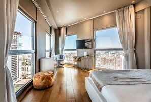A modern hotel room with a large bed, a seating area, and a view of the cityscape. - My Jerusalem View (Jerusalem)