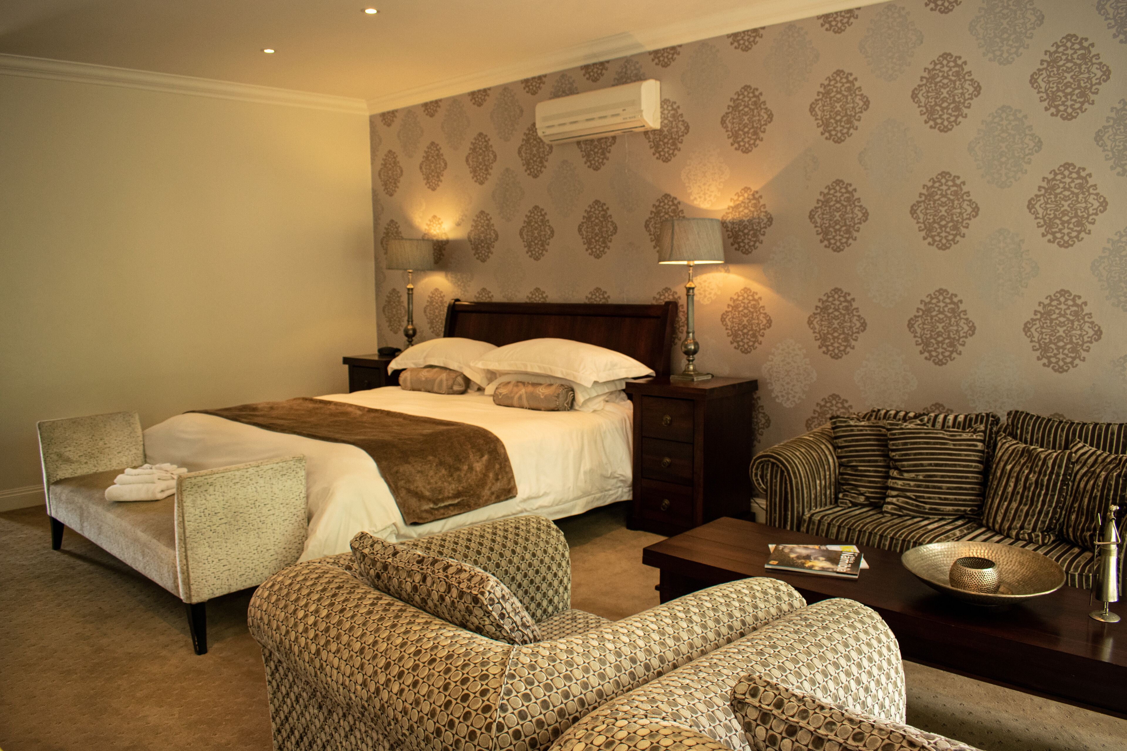 A bedroom with a large bed, two bedside tables with lamps, a sofa, and a coffee table.