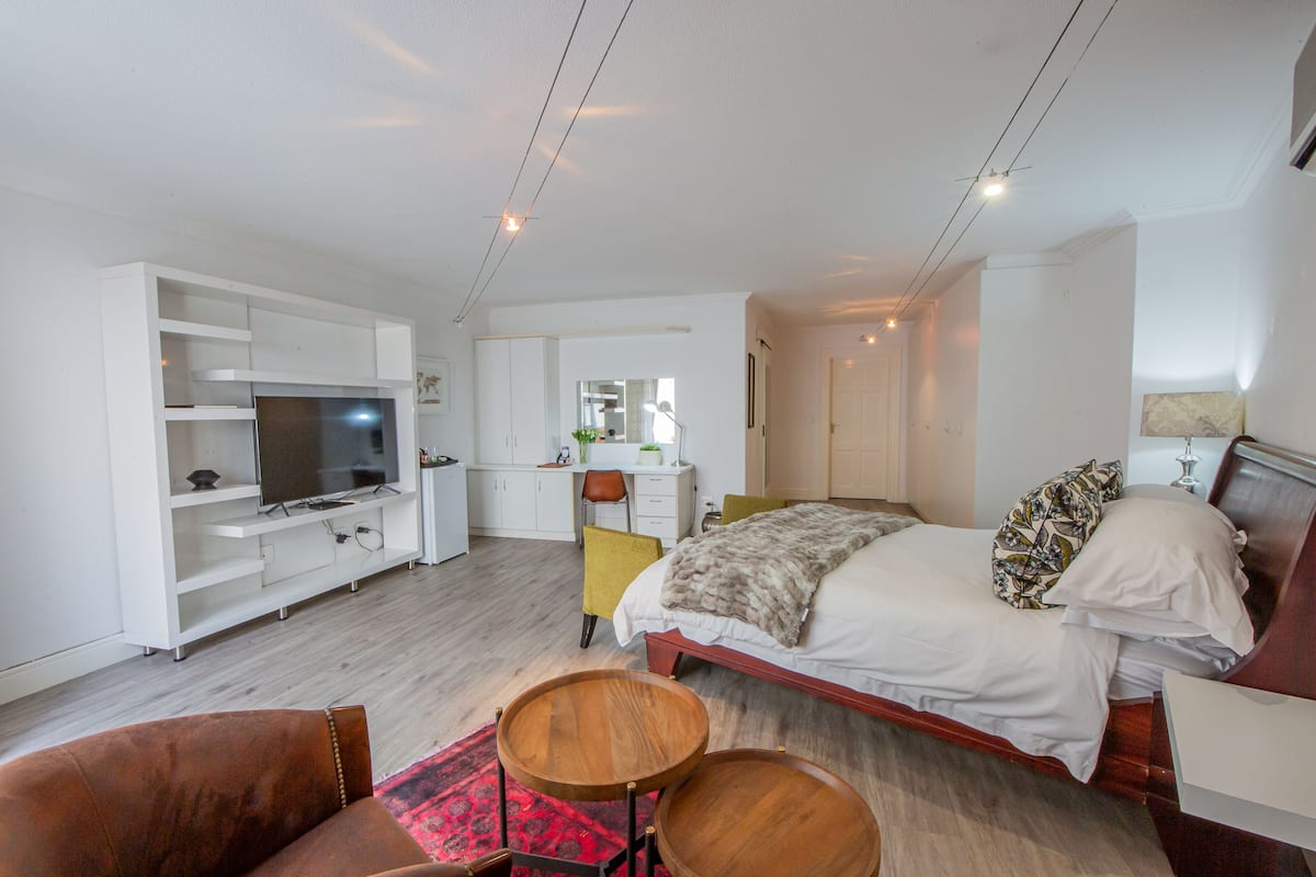 A modern hotel room with a bed, a TV, a desk, and a chair.