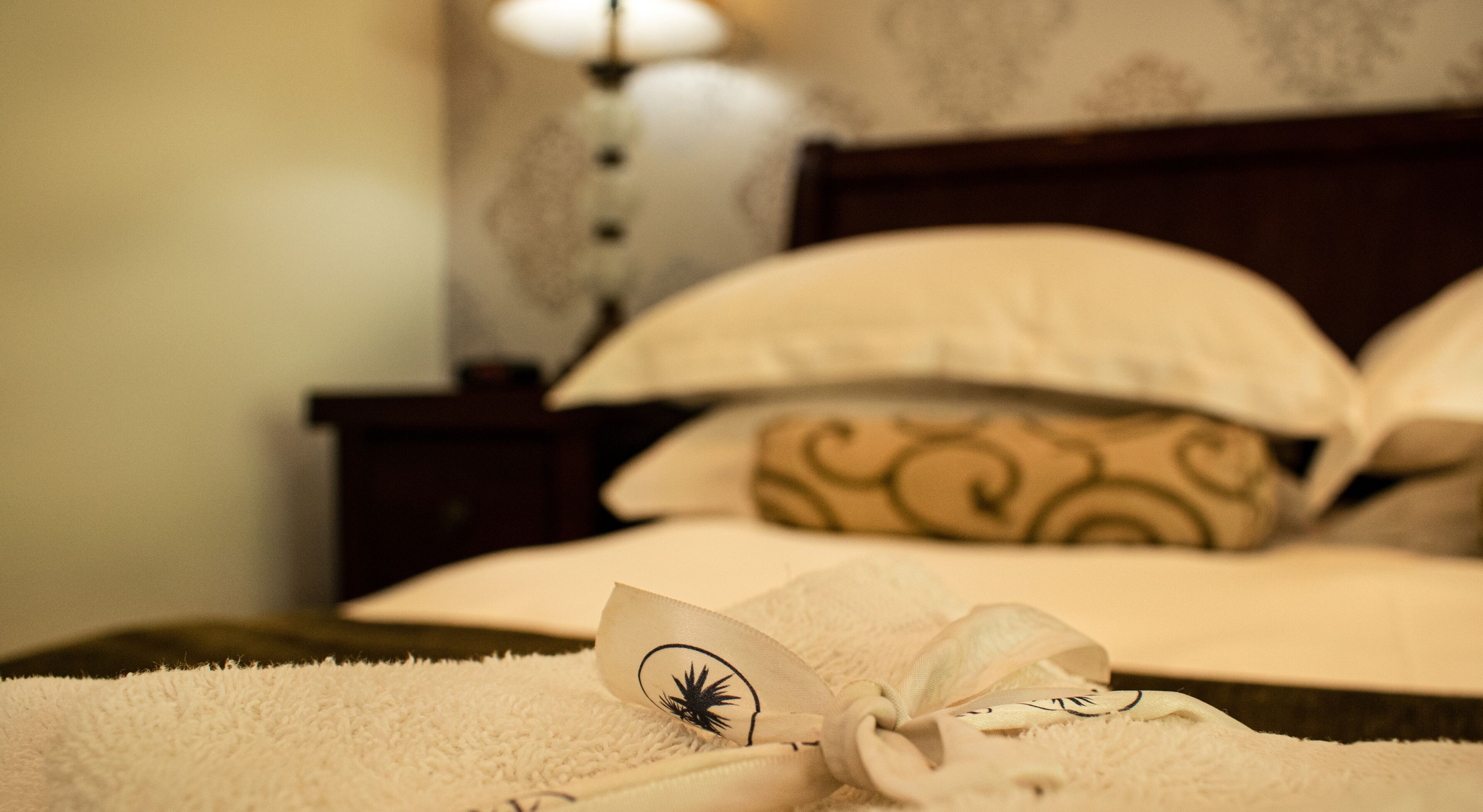 Un lit bien fait, avec une couette blanche et un coussin décoratif orné d’un motif cachemire.