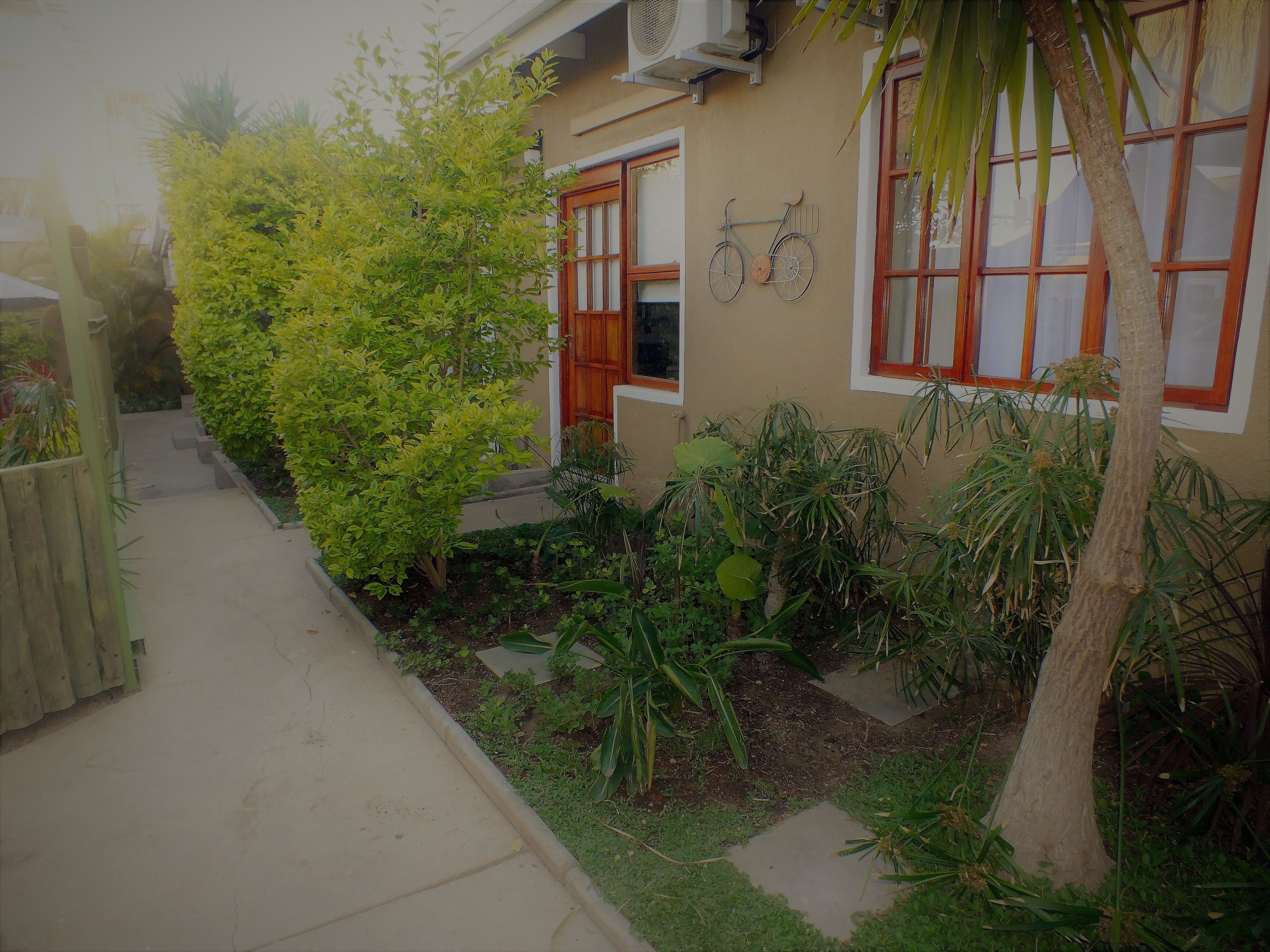 A house with a front yard, a wooden fence, and a bicycle mounted on the wall.